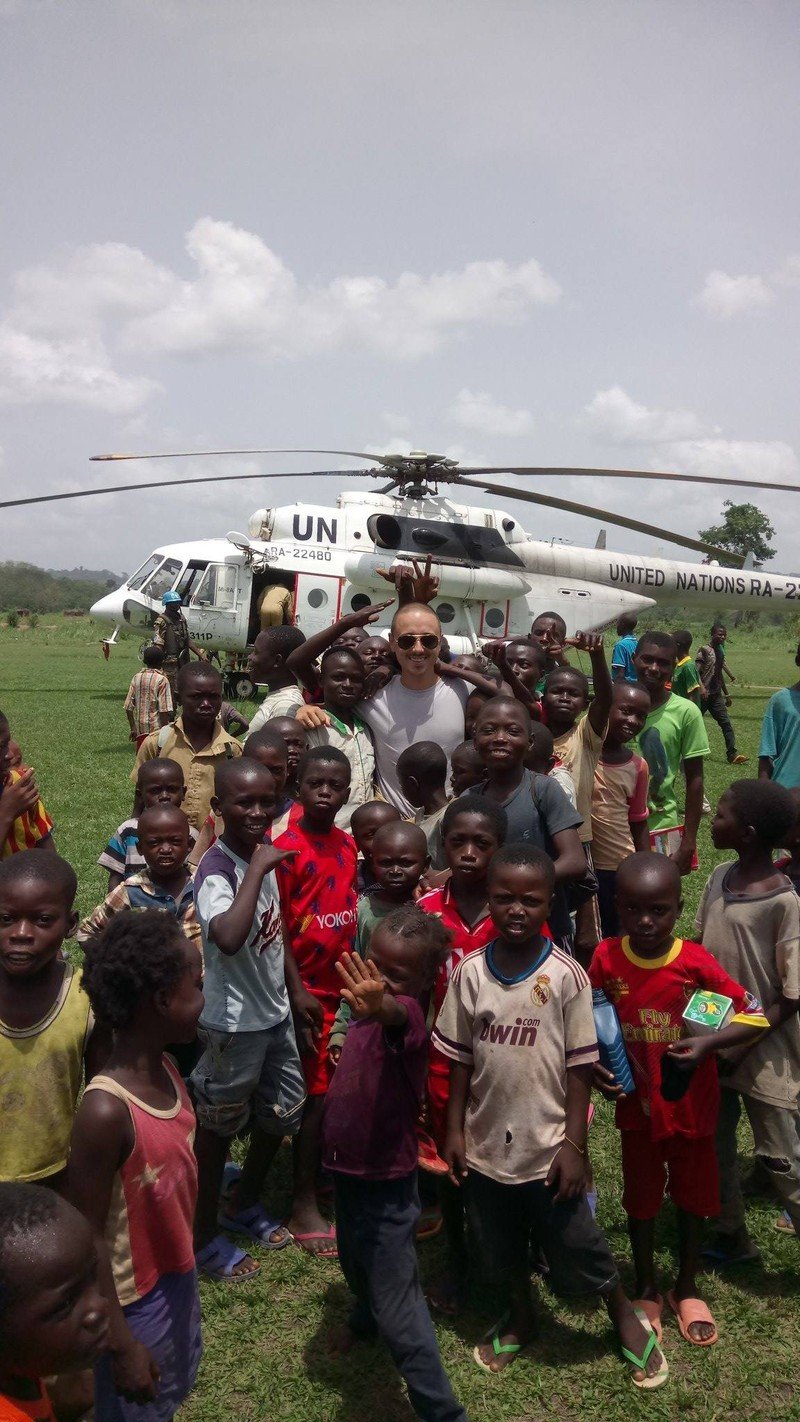 Pelican Flight School graduate with children near a UN helicopter.